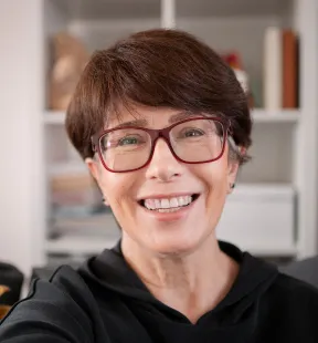 A woman in glasses smiling confidently