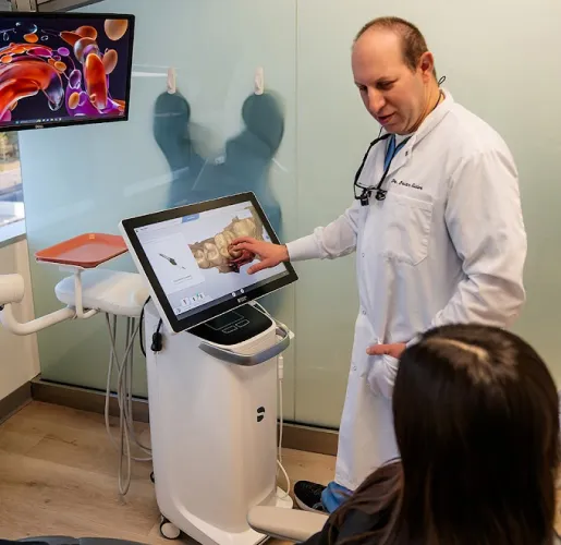 A dentist explaining scan results to a patient on a chairside monitor
